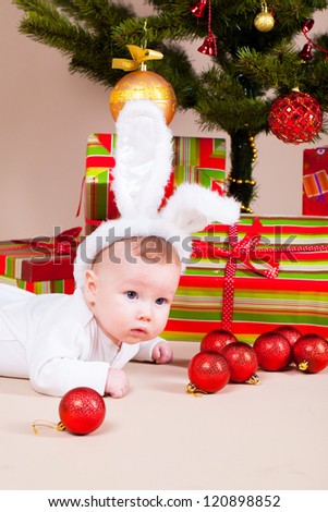 Little boy in rabbit hat laying under christmas pine