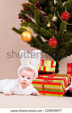 Little boy in rabbit hat laying under christmas pine