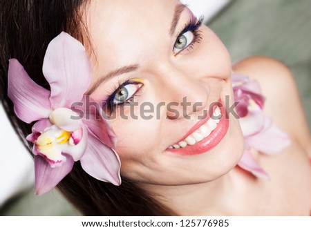 Beautiful brunette girl with orchid flowers in hair