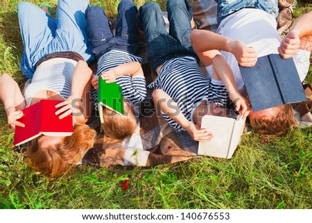 Family reading books laying on the grass