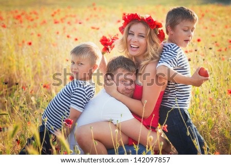 Family of four person playing on the poppy field