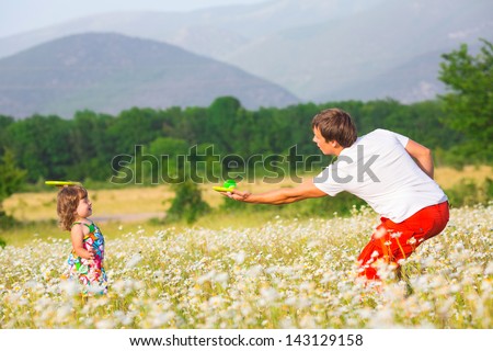 Father playing with daughter on the camomile meadow