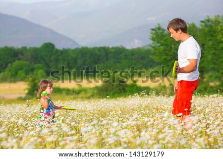 Father playing with daughter on the camomile meadow