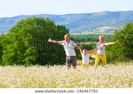 Family of three person on the camomile meadow