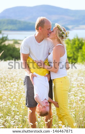 Family of three person on the camomile meadow
