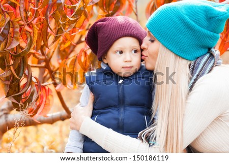 Beautiful woman with son in peach autumn garden