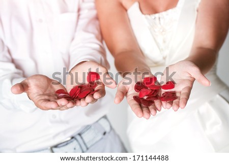 Young attractive just married couple showing red shapes in hands