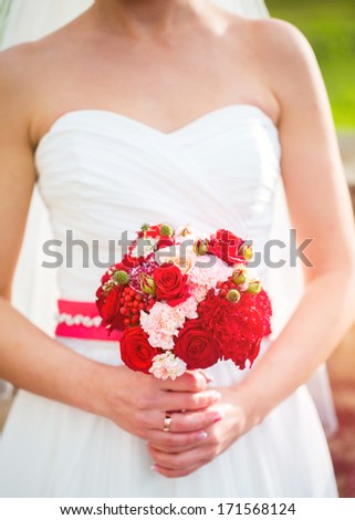 Beautiful red wedding bouquet in hands of the bride