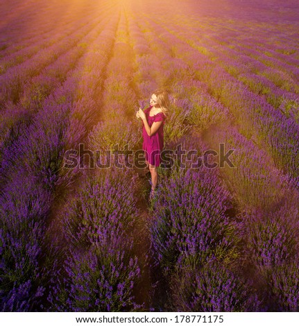 Beautiful girl on the lavender field under rays of sunrise