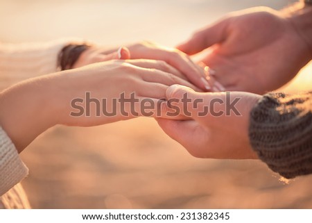 Two lovers holding their hands on the shore of the sea