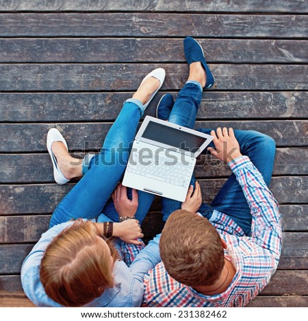 Young couple watching laptop sitting on the floor