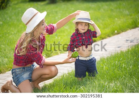 mom and son with funny hats sitting on the green grass.