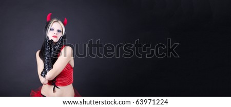 Young woman in devil dress on black background