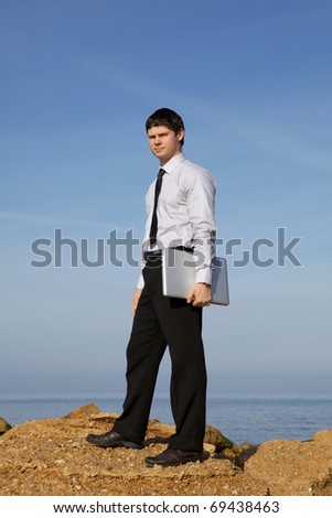 Man with laptop on the sea shore