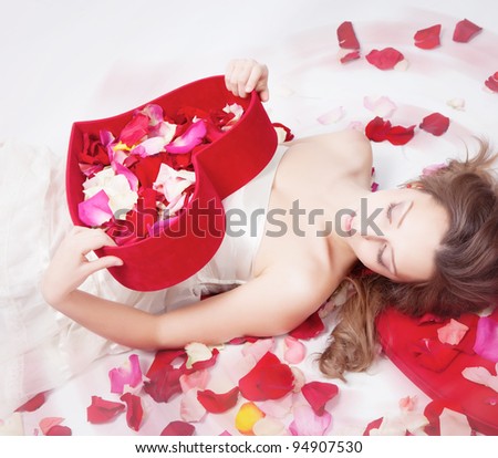 Beautiful girl with rose petals in heart form box
