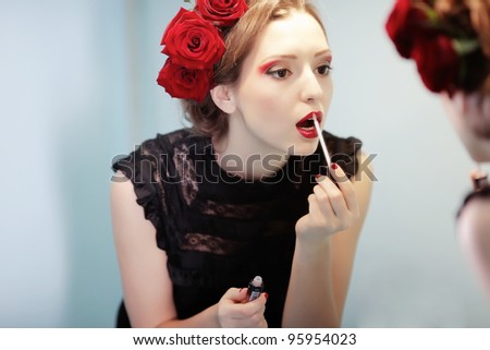 Beautiful girl with lipstick watching in mirror