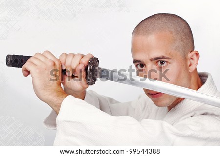 Youn man with japan sword in hands in studio