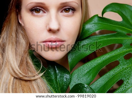 Girl face near green leaf in water drops