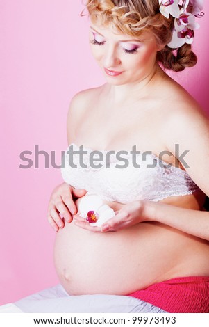 Beautiful pregnant woman with orchid flower in hair