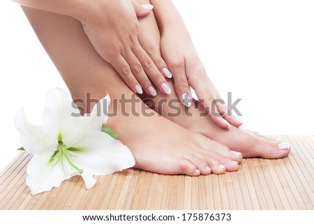 Elegant woman's manicured hand and pedicured feet with madonna lily on bamboo mat