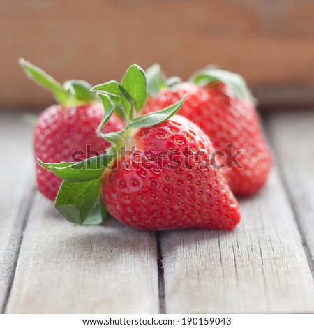 Fresh strawberries with leaves on an old wooden textured table top