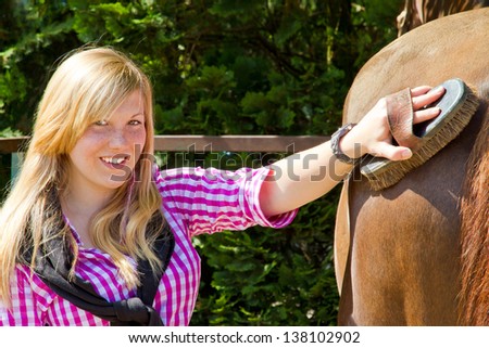 Teenager cleaning her horse