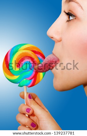 Beautiful girl licking on a colorful lolly