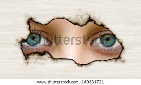 Eyes looking through a hole in paper