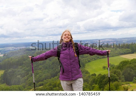 Young woman with hiking sticks top of the mountain