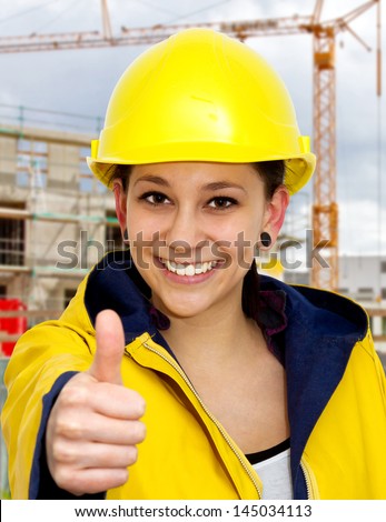 Young woman in work wear with thumb up