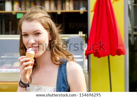Girl enjoy ice cream, in background a ice cream shop