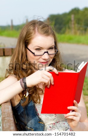 Woman with glasses reading a book in nature