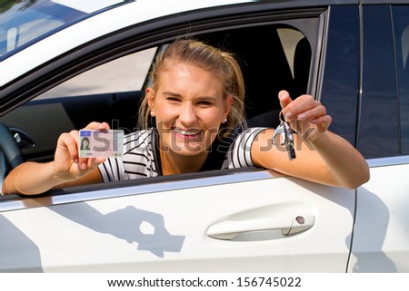 Happy girl in a car showing a key and her driver license