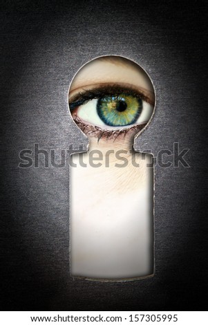 Eye looking through a metallic keyhole