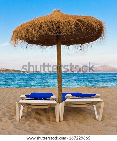 Umbrella and lounge chairs on the beach of Pollenca, Mallorca