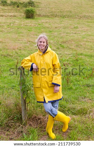 Happy girl in a yellow raincoat and rubber boots
