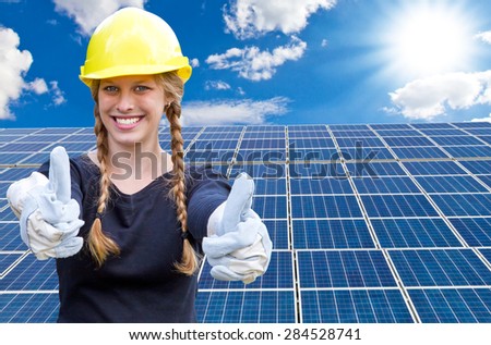 Happy young woman standing in front of solar panels