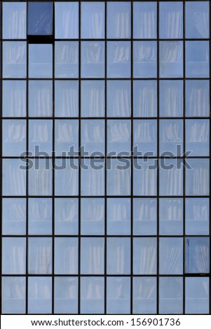 Grid of office blue windows with curtains.