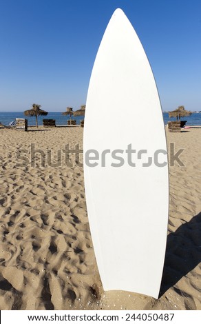White surfboard is stuck in the sand.