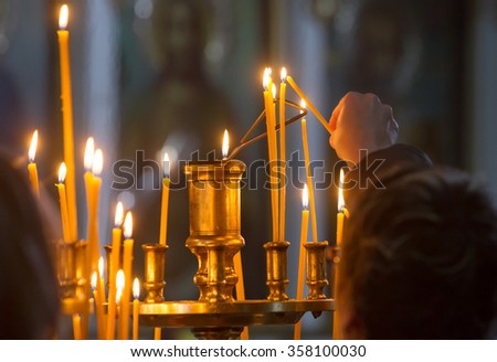 Woman hand lighting candles in a church.