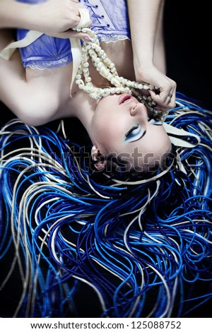 Gothic looking female with blue and white dread hairstyle with pearl necklace upside down on black background
