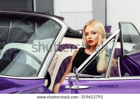 Beautiful woman is sitting in the car and touching her blond hair