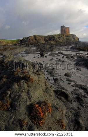 Ruined Scottish castle overlooks rocks as tide goes out