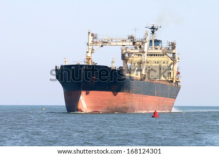 Old cargo ship sailing in still water near port