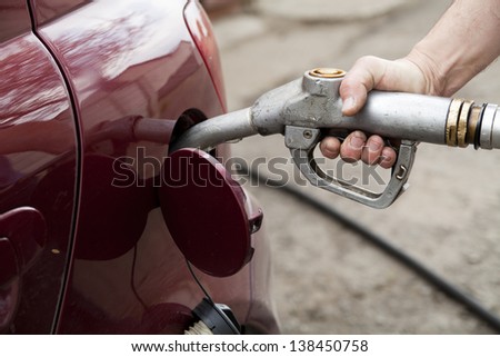 close-up of a hand pumping gas in the car with a gas pump