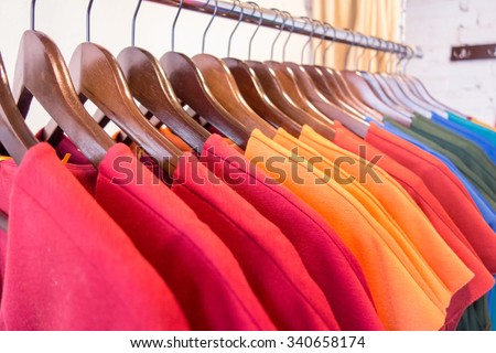 Line of multi colored clothes on wooden hangers in store. Sale