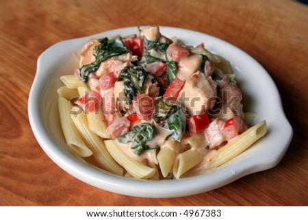 Penna pasta with sauteed chicken, red pepper, spinach, and tomatoes in cream sauce
