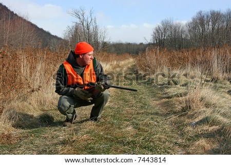 A man hunting in field with gun