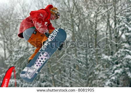 A snowboarder jumping in air at snowboarding competition