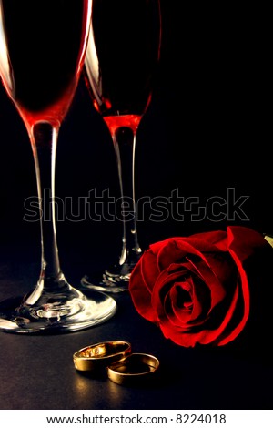 stock photo Wedding rings rose and champagne glasses over black